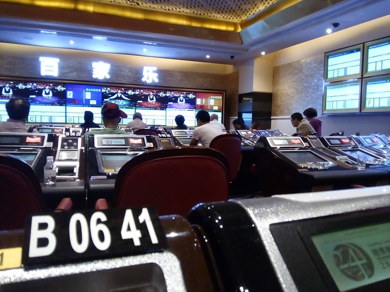 百家樂電子牌桌大廳，牆面顯示多桌真人百家樂畫面